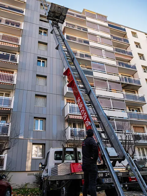 Technicien surveillant la montée d'un monte-meubles sur un immeuble à Lyon